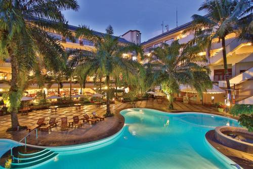a hotel with a swimming pool and palm trees at The Jayakarta Suites Bandung in Bandung