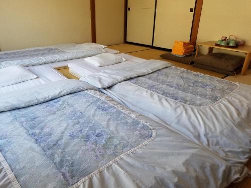 a group of three beds sitting in a room at Ryokan Matsukaze in Matsumoto