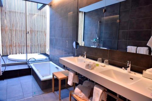 een badkamer met een bad, een wastafel en een spiegel bij The Meibia Miyazaki in Miyazaki