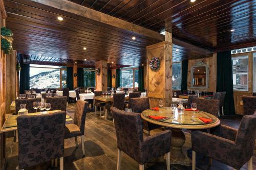 un restaurant avec des murs en bois, des tables et des chaises dans l'établissement Madame Vacances Hôtel & Spa Le Mottaret, à Méribel