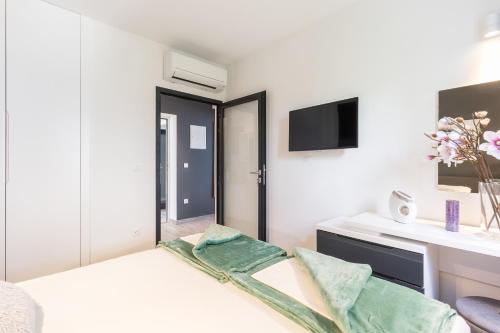 a white bedroom with a bed and a tv at Residence Alpha Apartments in Cavtat