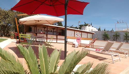 a red umbrella and some chairs and a building at bolinajazz in Lampedusa