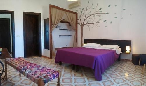 a bedroom with a purple bed and a tree on the wall at bolinajazz in Lampedusa