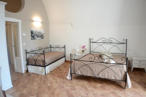 two metal beds in a room with wooden floors at B&B Fontana La Stella in Gravina in Puglia