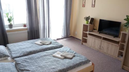 two beds in a room with a television and towels at Apartmá Anglická in Františkovy Lázně