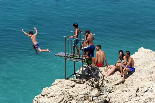 a group of people jumping off a cliff into the water at Hotel Nimfa in Vlorë