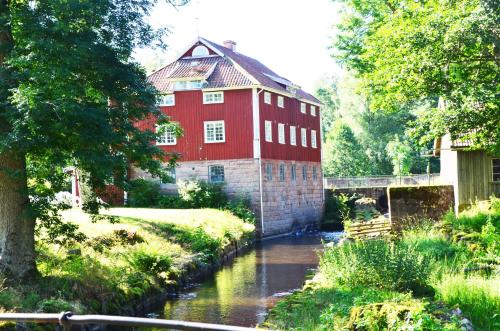 a red building with a river in front of it at Vandrarhemmet Årås Säteri och Trädgårdar in Årås