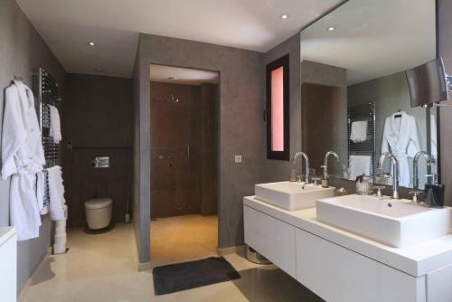 Villa Riad Al Maaden في مراكش: حمام به مغسلتين ومرآة كبيرة