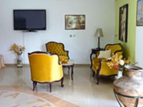a living room with yellow chairs and a flat screen tv at Castellania Hotel Apartments in Livadia