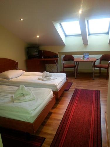 カトヴィツェにあるHotel Restauracja Kingaのベッド2台、テーブル、椅子が備わる客室です。
