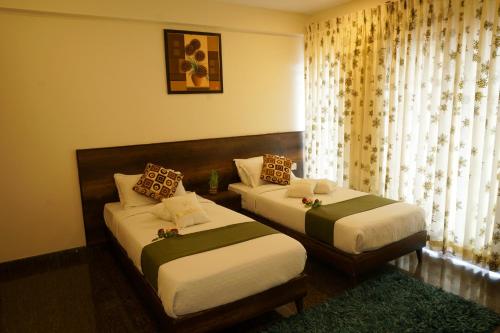 a bedroom with two beds and a window with curtains at Royal Serenity - Kammanahalli in Bengaluru