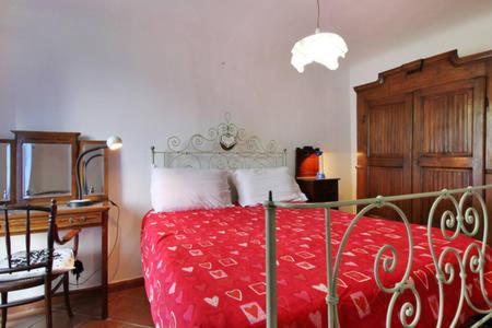 a bedroom with a bed with a red bedspread and a desk at Apartment Poesia in Bagni di Lucca