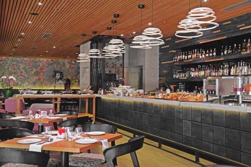 a restaurant with tables and a bar with wine bottles at The Capital Menlyn Maine in Pretoria