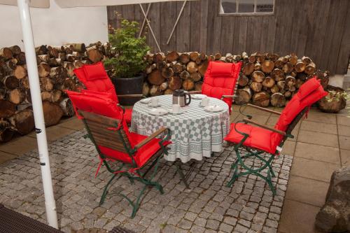 uma mesa e quatro cadeiras com almofadas vermelhas num pátio em Georg Mayer Haus em Oberstdorf