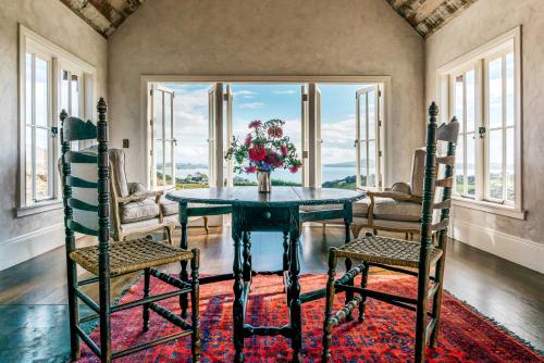 uma sala de jantar com uma mesa e duas cadeiras em Mudbrick Cottages em Oneroa