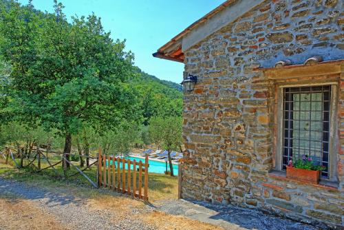 a stone building with a window and a fence at Villa Poggio Conca by PosarelliVillas in Incisa in Valdarno