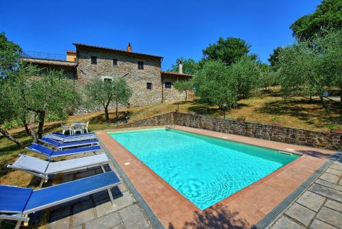 an outdoor swimming pool with chairs and a house at Villa Poggio Conca by PosarelliVillas in Incisa in Valdarno
