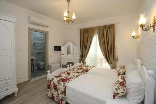 a bedroom with a white bed and a bathroom at Alya Mou Butik Hotel in Cesme