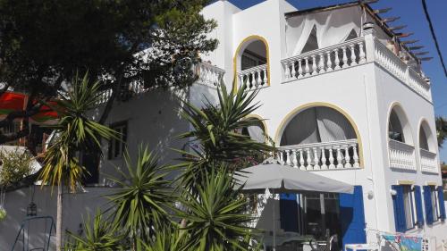 a white building with palm trees in front of it at Wavedance Accommodation in Salamís