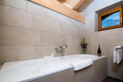 a white bath tub in a bathroom with a window at Sonnegg Penthouse in Saas-Fee