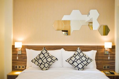 タンゲランにあるゴールデン チューリップ エッセンシャル タンゲランのベッドルーム(白いベッド、枕、照明付)