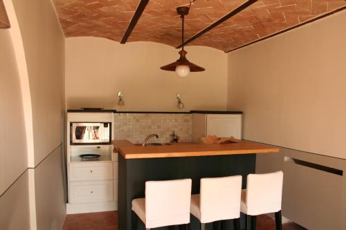 a kitchen with white chairs and a counter top at Relais Azienda Casalino in Toppole