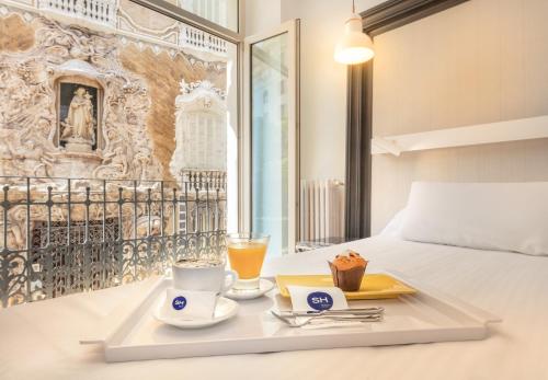 a tray with two cups and drinks on a bed at SH Ingles Boutique Hotel in Valencia