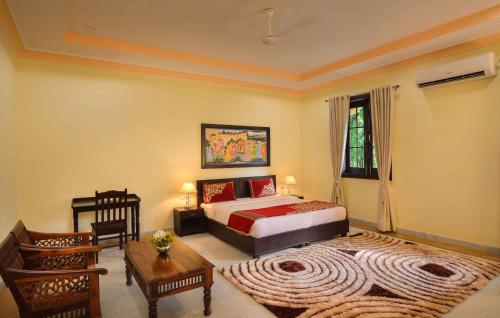 a bedroom with a bed and a table and chairs at Syna Heritage Hotel in Khajurāho