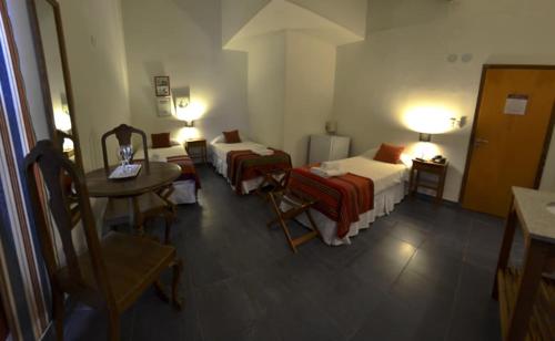 a hotel room with two beds and a table and a desk at Hotel La Cautiva de Ramirez in La Paz