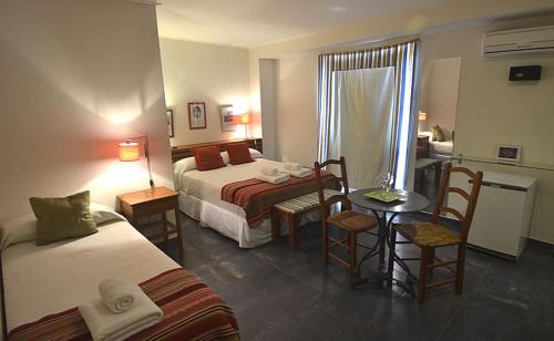 a hotel room with two beds and a table and chairs at Hotel La Cautiva de Ramirez in La Paz