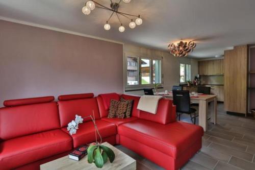 sala de estar con sofá rojo y cocina en Wildhaus Weiherhof, en Wildhaus