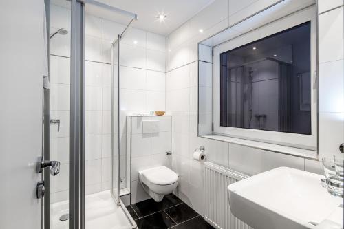 
a white toilet sitting next to a bath tub in a bathroom at Hotel La Scala in Gelsenkirchen
