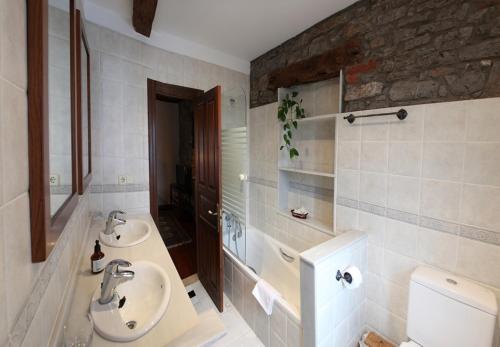 a bathroom with two sinks and a toilet at Casa de Aldea La Pumariega in Caces