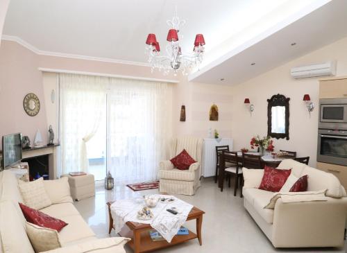 salon z białymi meblami i żyrandolem w obiekcie Athina Luxury Apartment w mieście Keramotí