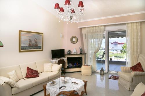 salon z białymi meblami i żyrandolem w obiekcie Athina Luxury Apartment w mieście Keramotí