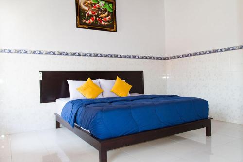 Wahyu Homestay 2 في نوسا ليمبونغان: غرفة نوم بسرير ذو شراشف زرقاء ومخدات صفراء