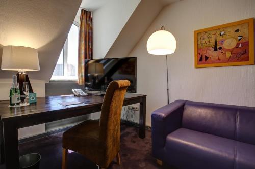 a hotel room with a desk with a couch and a tv at Trip Inn Hotel Blankenburg in Karlsruhe