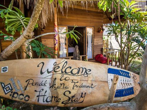 a surfboard sitting in front of a house at Pondok Kana And Hostel by Ecommerceloka in Nusa Penida
