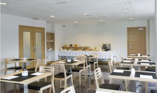 un comedor con mesas blancas y sillas blancas en Aginaga Hotela en Usúrbil