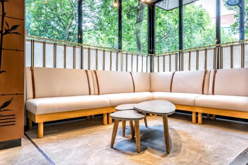 a couch and two tables in a room with windows at Hotel Restaurant Au Boeuf Couronné in Paris