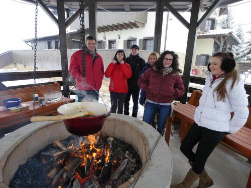 a group of people standing around a fire pit at Pensiunea Vis Alpin Belis in Beliş