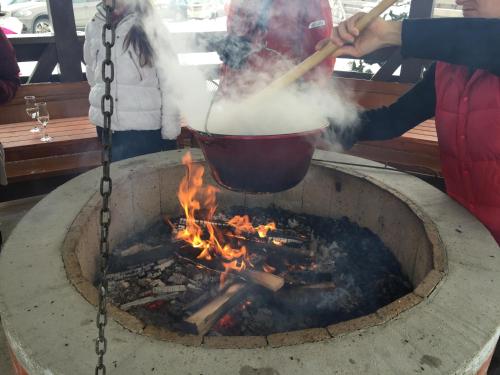 a woman cooking in a pot over a fire at Pensiunea Vis Alpin Belis in Beliş