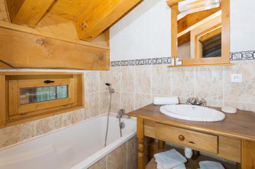 a bathroom with a sink and a bath tub at Madame Vacances Les Chalets De La Tania in La Tania