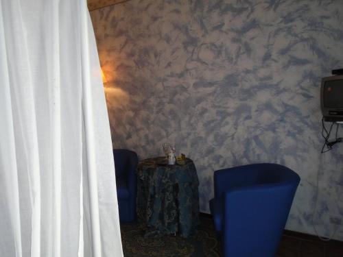 a room with two blue chairs and a table and a curtain at Bellavista in Pettenasco