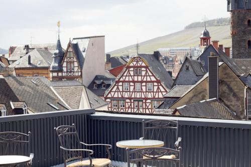 a group of chairs and tables on a balcony with buildings at Weingut & Gästehaus Schmitz-Bergweiler in Bernkastel-Kues