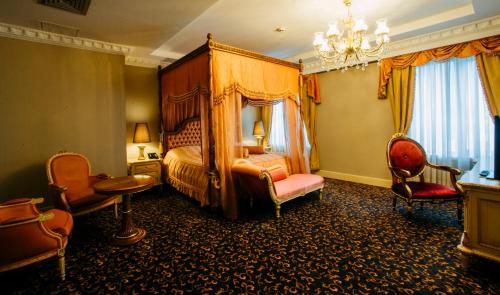 a bedroom with a bed and chairs and a chandelier at Hotel Intourist Palace Batumi in Batumi