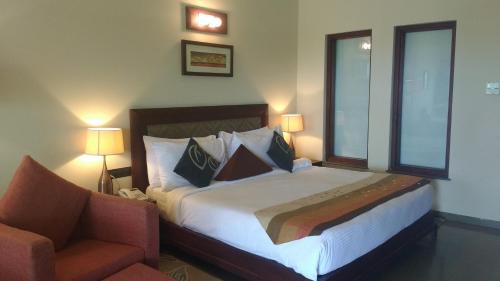 a hotel room with a bed and a chair at Gulmohar Greens Golf & Country Club in Sānand