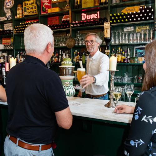a man standing at a bar with a bartender at Hotel Restaurant Taverne in Twello