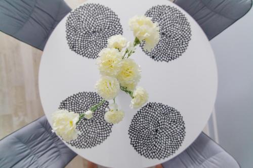 a person holding a white plate with flowers on it at Dwie Sosny - Apartament 48 in Ustronie Morskie