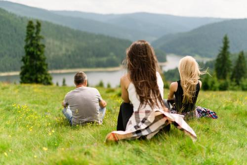 a group of people sitting in a field of grass at Pensiunea Vis Alpin Belis in Beliş